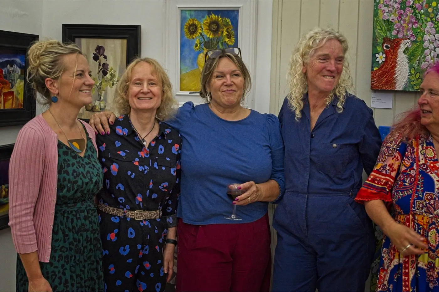 Six smiling artists and friends at the exhibition, one holding a small dog